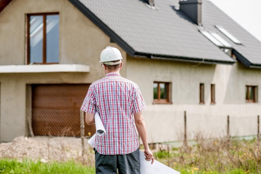 A contractor with plans in front of a house