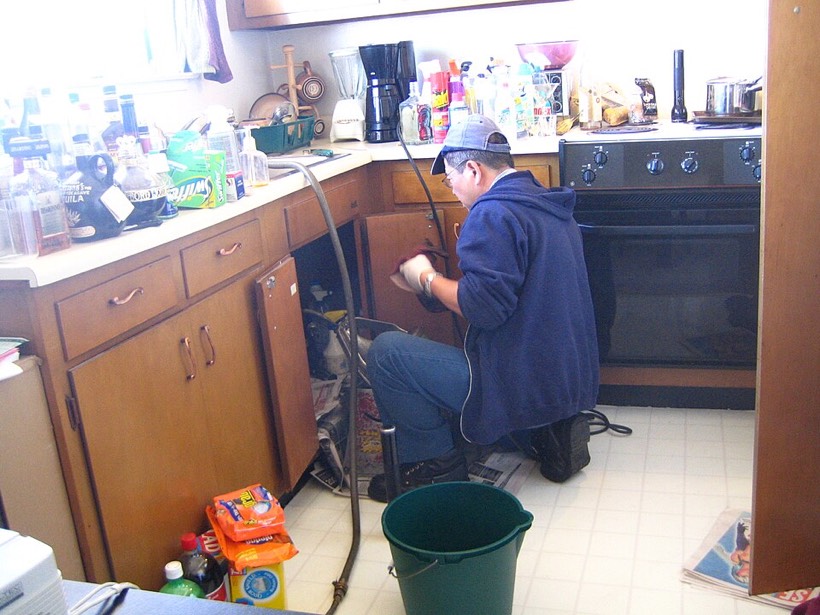 Plumber working under a sink